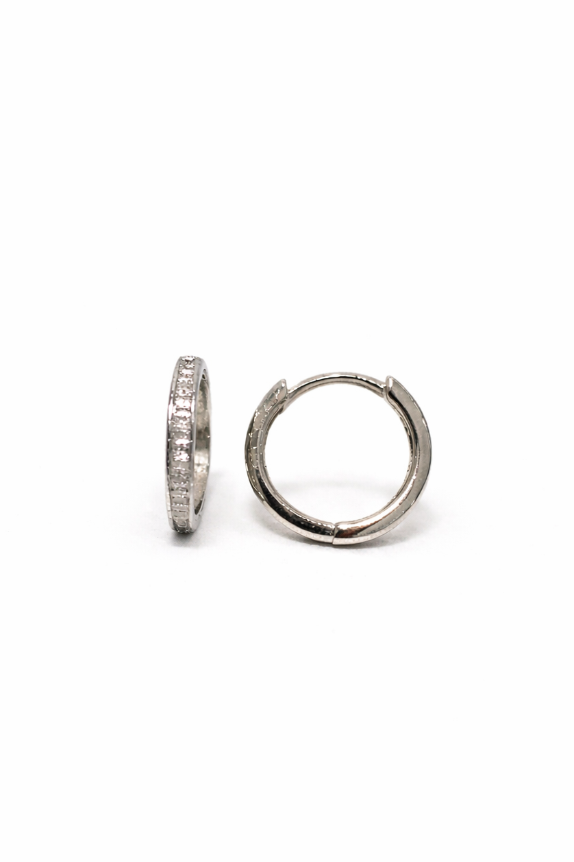 Pair of white gold and baguette diamond hoop earrings on a white background