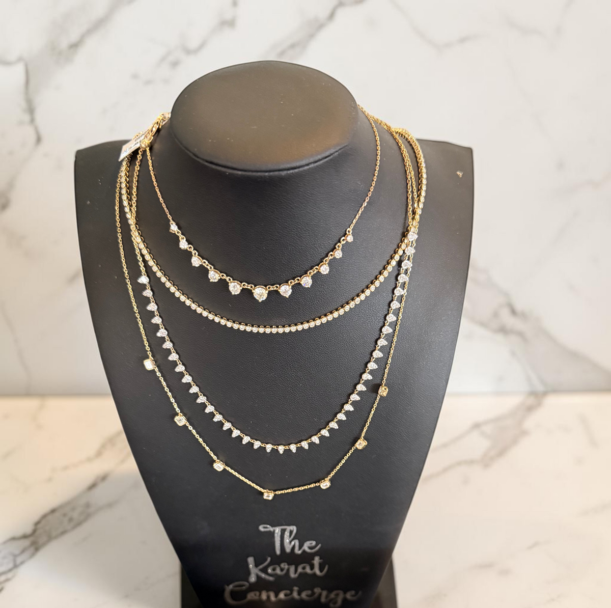 The Karat Concierge Sloane bezel emerald cut natural diamond necklace in 14K yellow gold on a black display bust