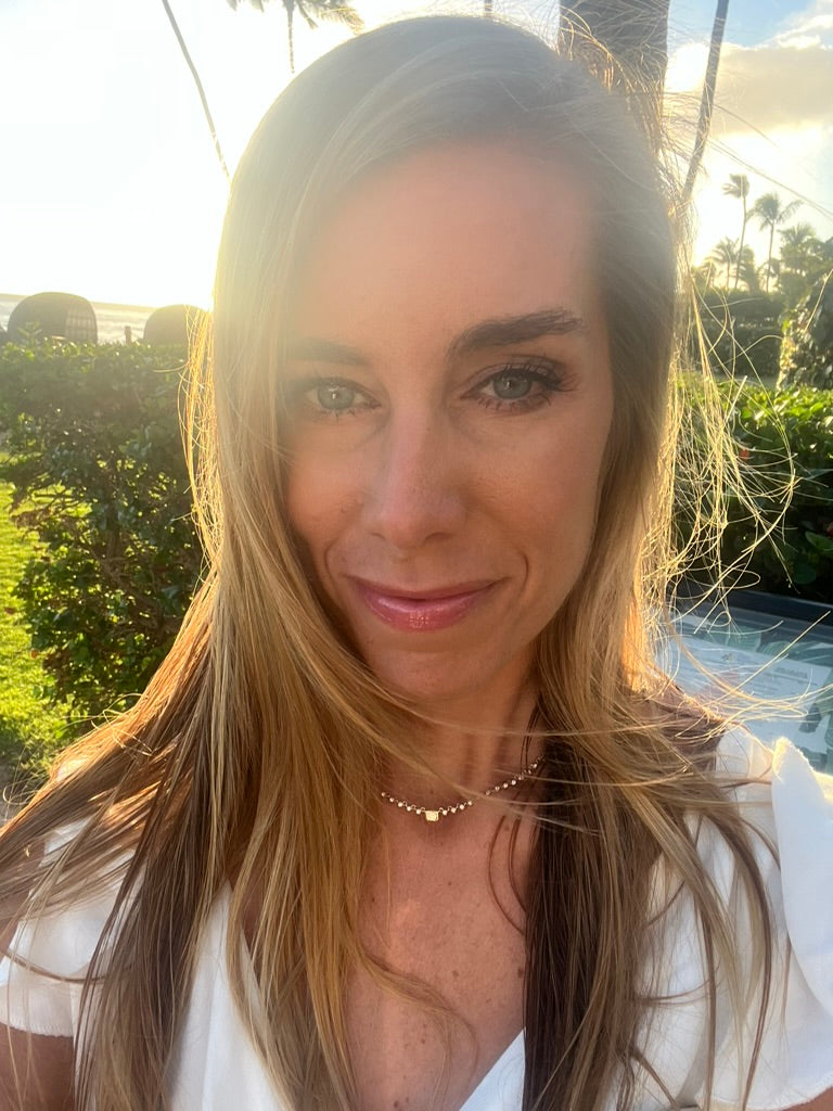 woman wearing gold and diamond necklace with emerald cut diamond in the middle