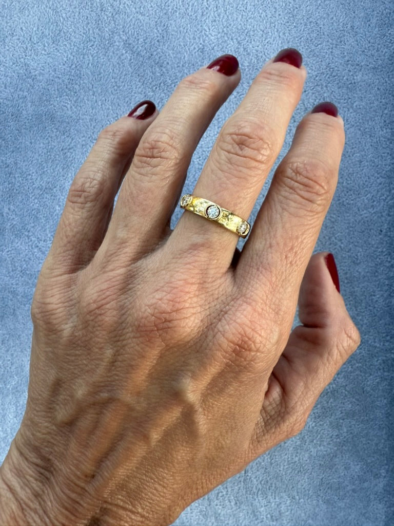 Hand wearing a gold ring with a blue background