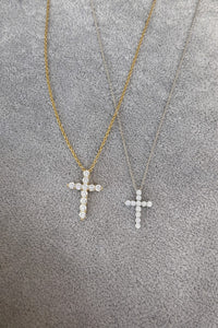 Two gold cross necklaces on a textured gray surface