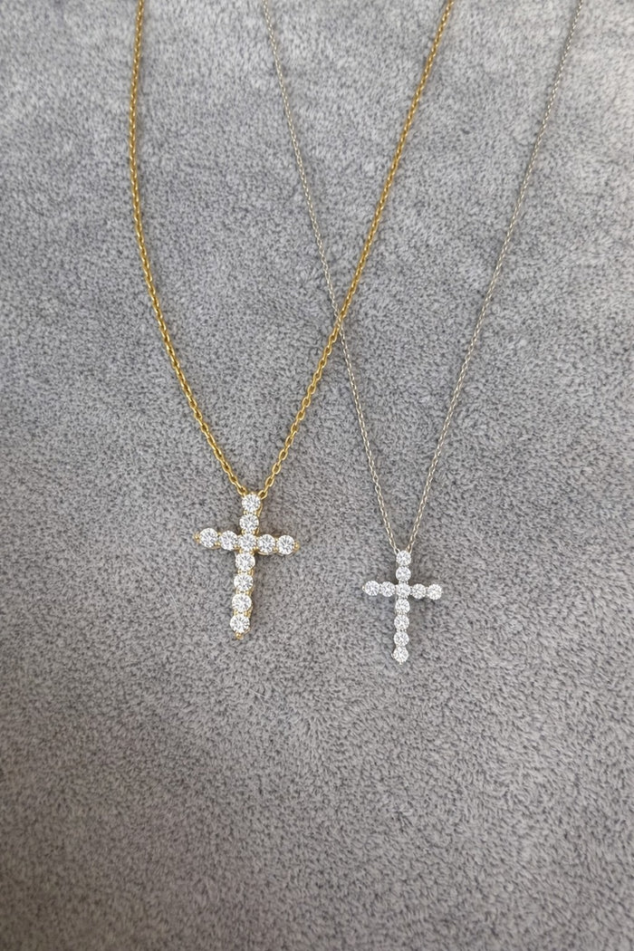 Two gold cross necklaces on a textured gray surface