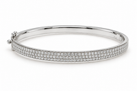 A polished silver-tone hinged bangle bracelet paved with small clear gemstones on the front band, shown on a clean white background.