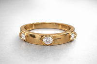 Gold ring with three diamonds on a light gray background