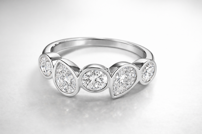 Silver ring with four diamonds on a light gray background