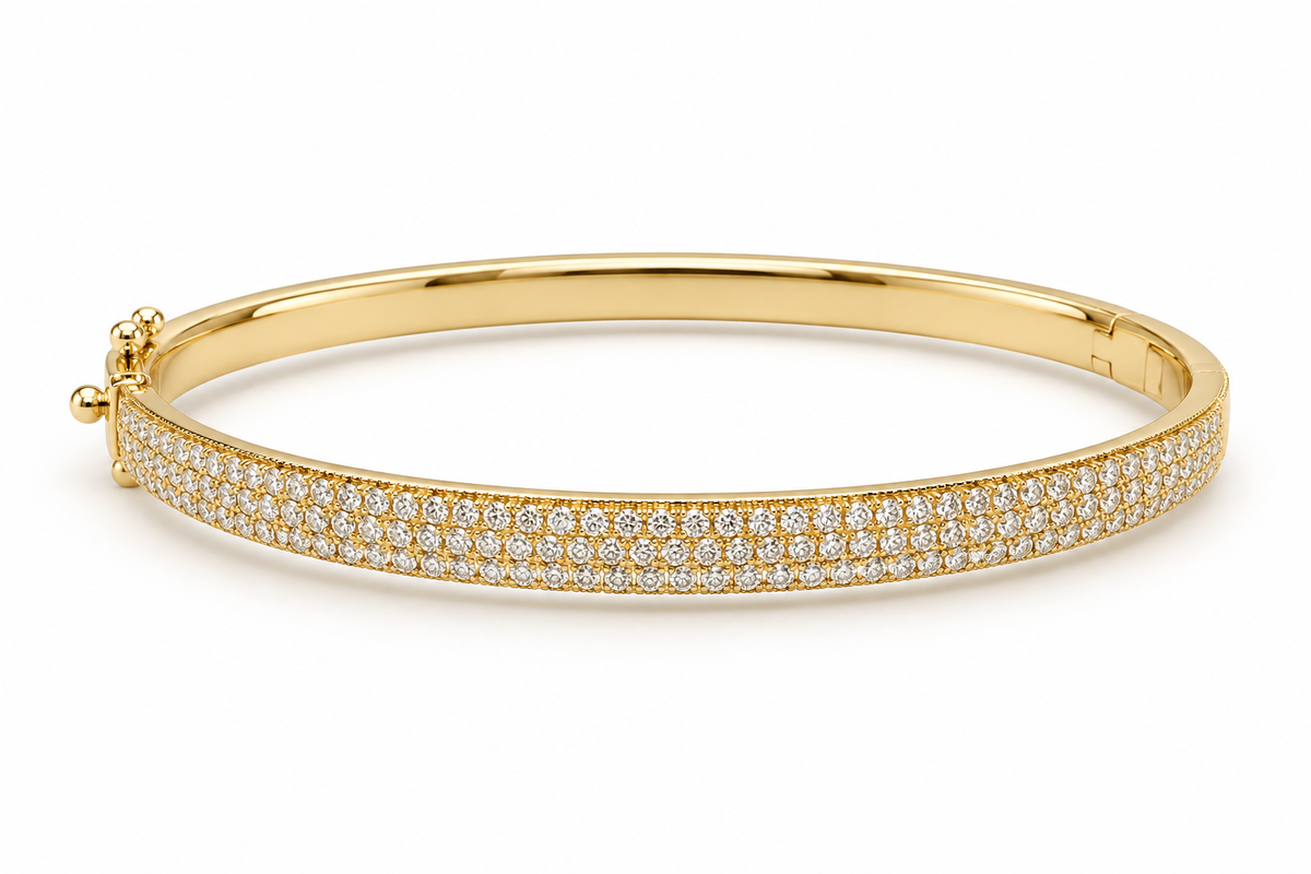 A polished yellow gold hinged bangle bracelet featuring a double row of pave-set round diamonds along the outer band, shown on a clean white background.