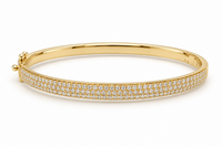 A polished yellow gold hinged bangle bracelet featuring a double row of pave-set round diamonds along the outer band, shown on a clean white background.