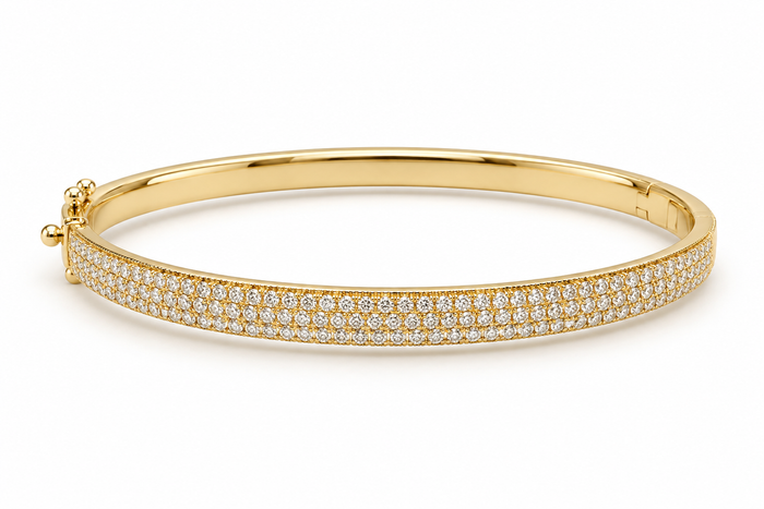 A polished yellow gold hinged bangle bracelet featuring a double row of pave-set round diamonds along the outer band, shown on a clean white background.
