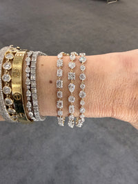 Close-up of a wrist wearing multiple diamond bracelets on a gray background