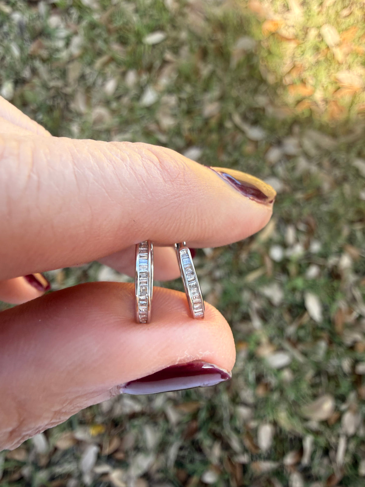 Pair of white gold and baguette diamond hoop earrings on a nature background
