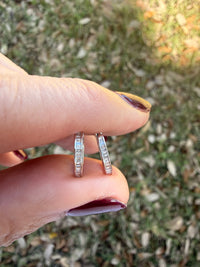 Pair of white gold and baguette diamond hoop earrings on a nature background