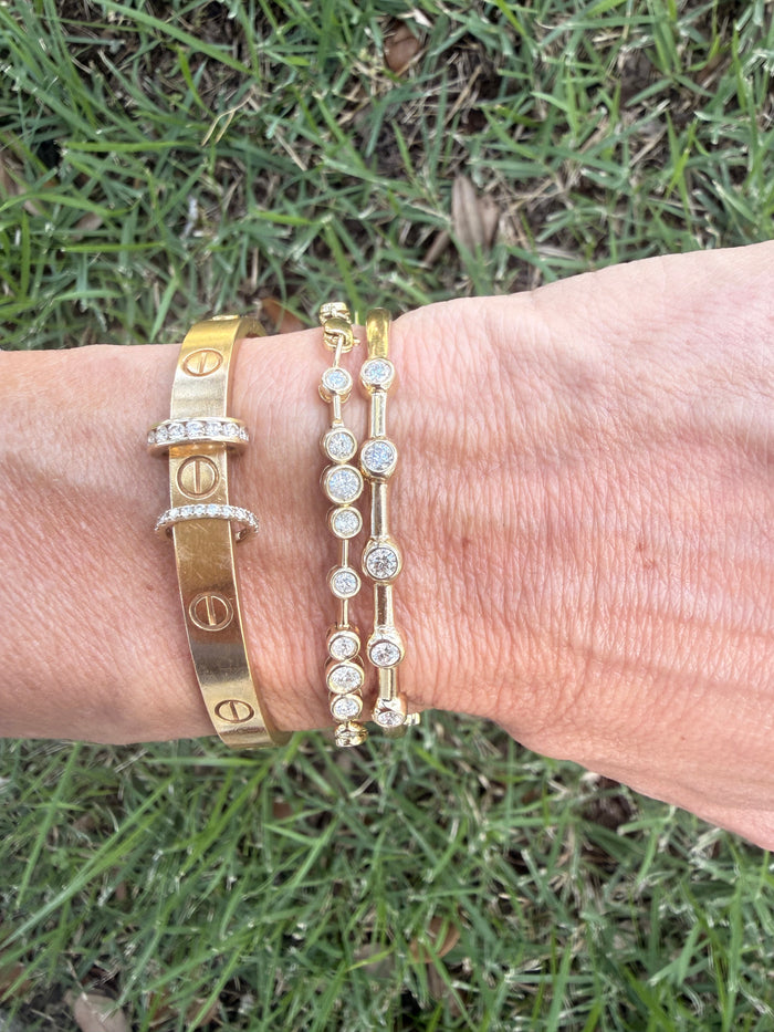 Gold bracelets on a wrist with a grassy background