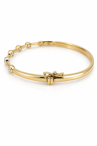 Gold bracelet with bow detail on a white background