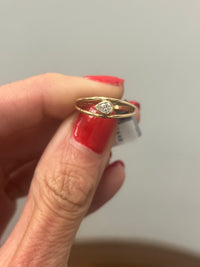 hand holding a yellow gold ring with a bezel set pear shaped diamond