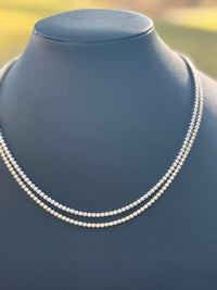 2 Diamond necklaces on a mannequin with a blurred natural background