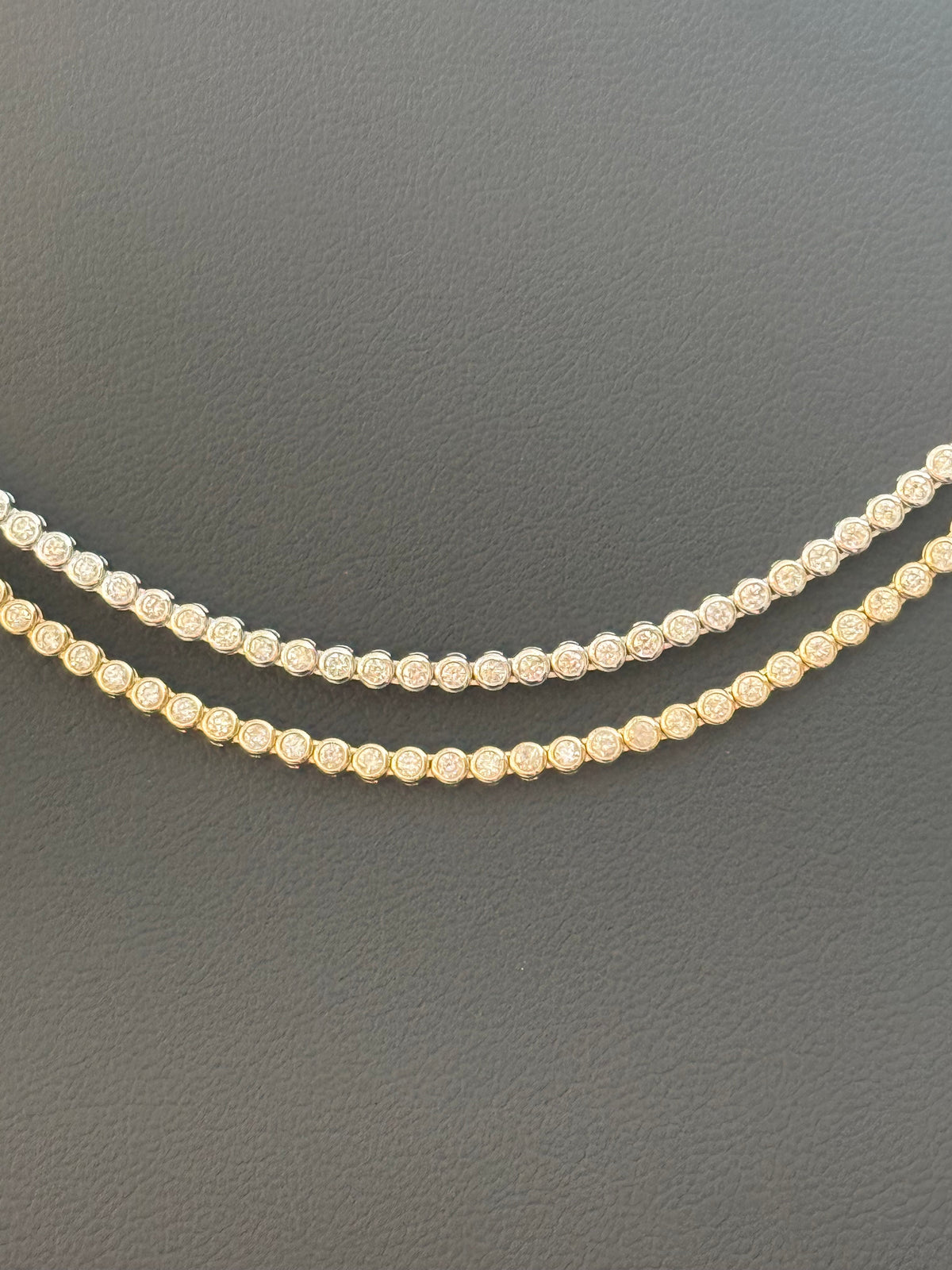 Two diamond necklaces on a dark gray background