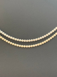 Two diamond necklaces on a dark gray background