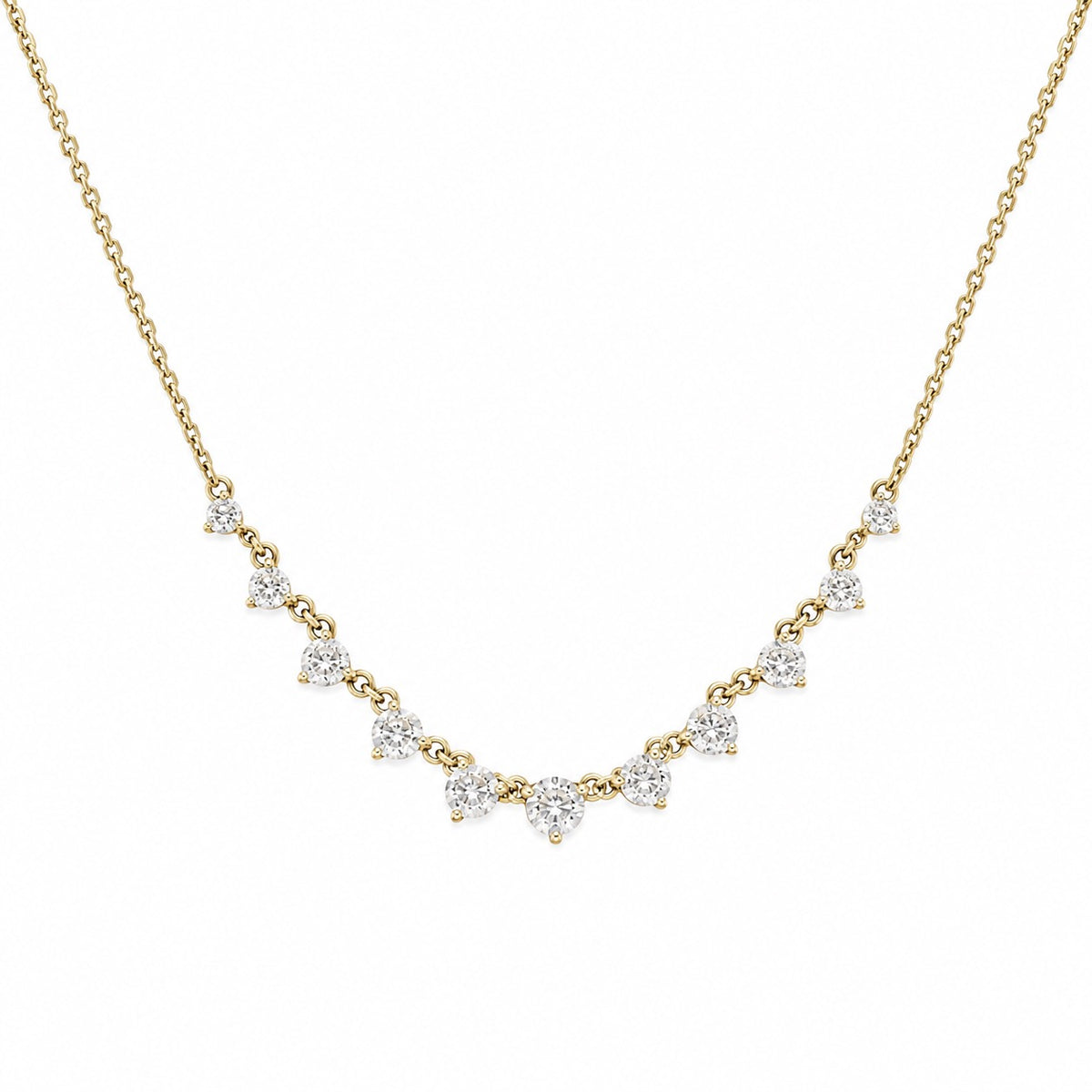 A delicate yellow gold chain necklace featuring a curved row of small, clear triangular gemstones in prong settings, displayed against a solid white background.