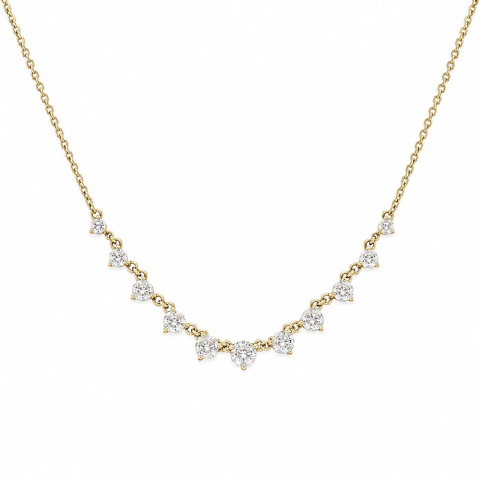 A delicate yellow gold chain necklace featuring a curved row of small, clear triangular gemstones in prong settings, displayed against a solid white background.