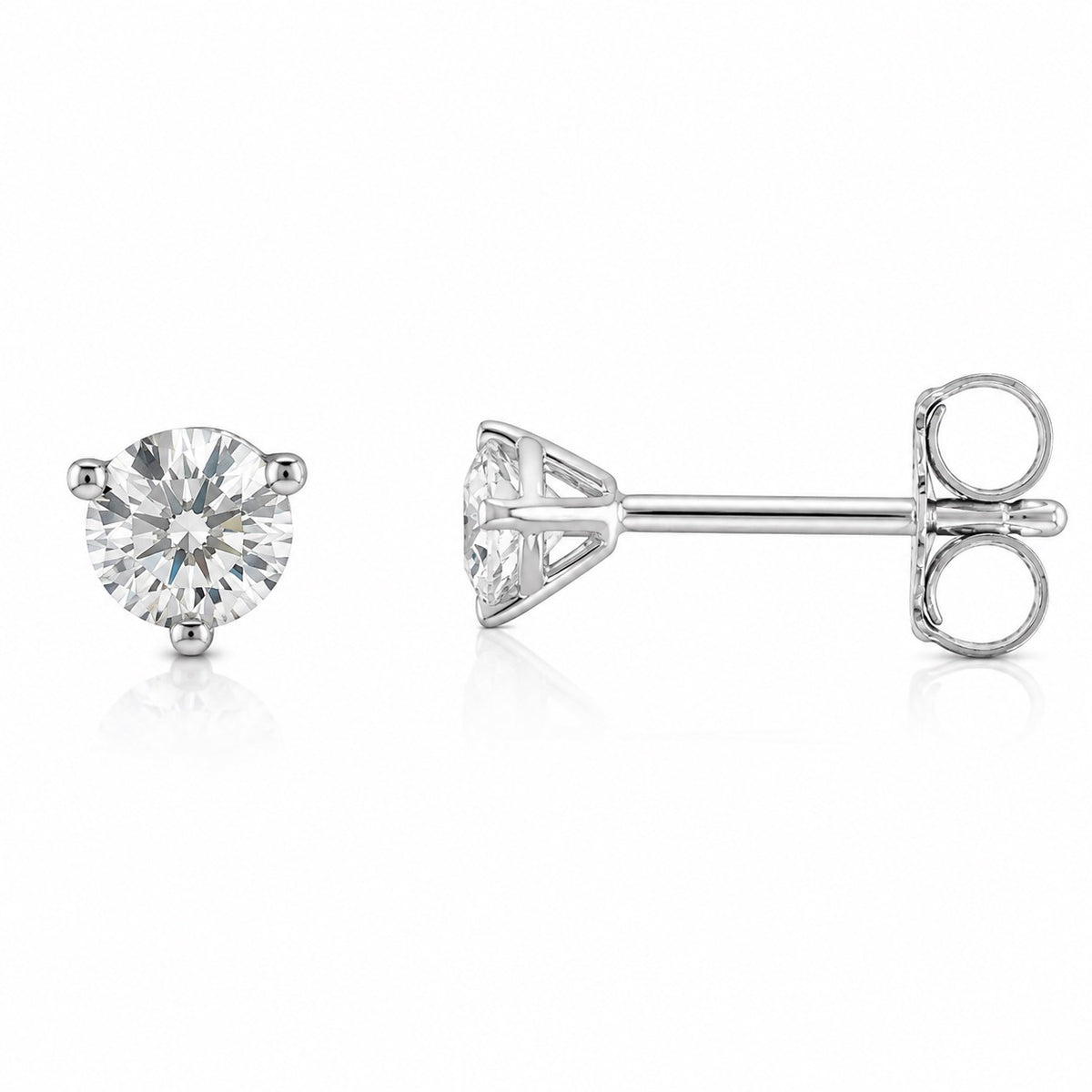 A pair of round-cut diamond stud earrings in silver-tone four-prong settings, shown on a clean white background with one earring facing forward and the other showing the side profile with butterfly backing.