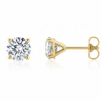 A pair of yellow gold stud earrings, one shown from the front with a round brilliant-cut clear gemstone and the other from the side showing the triangular prong setting and post with butterfly back, on a white background with a soft reflection.