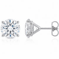 A pair of silver stud earrings, featuring one round-cut diamond solitaire and one triangular-cut diamond with a side stone, set in polished silver-toned metal on a white background.