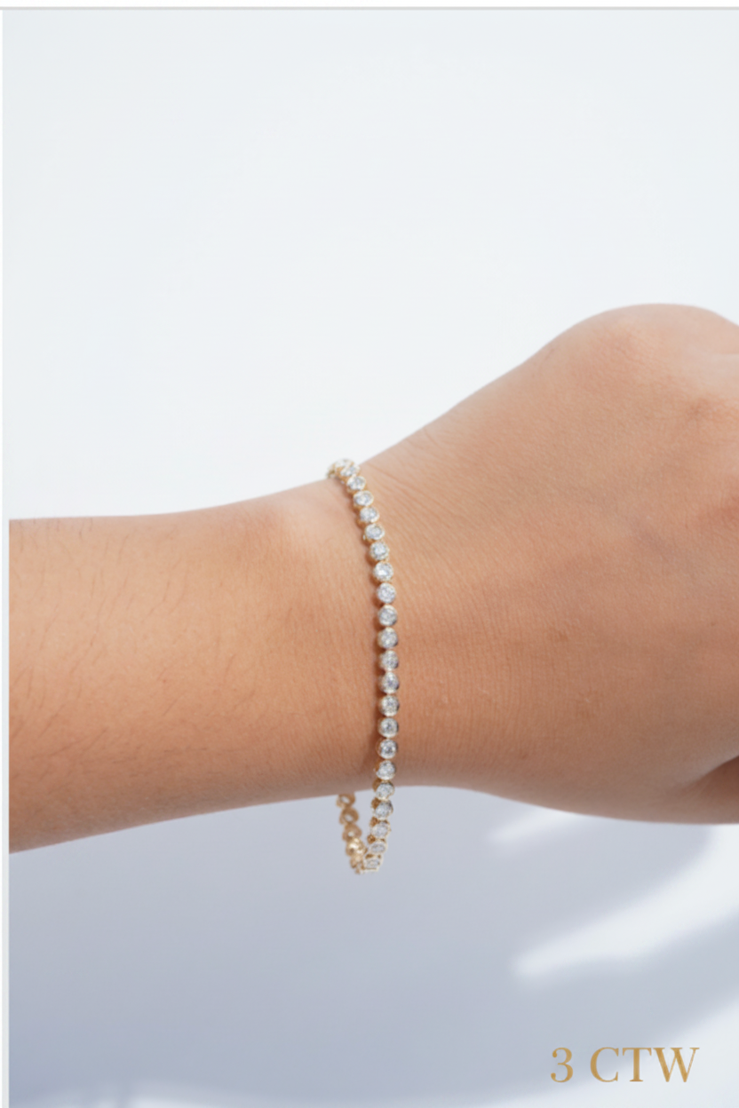 A delicate tennis bracelet with small diamonds set in a gold-tone band, shown worn on a person's wrist against a clean white background.