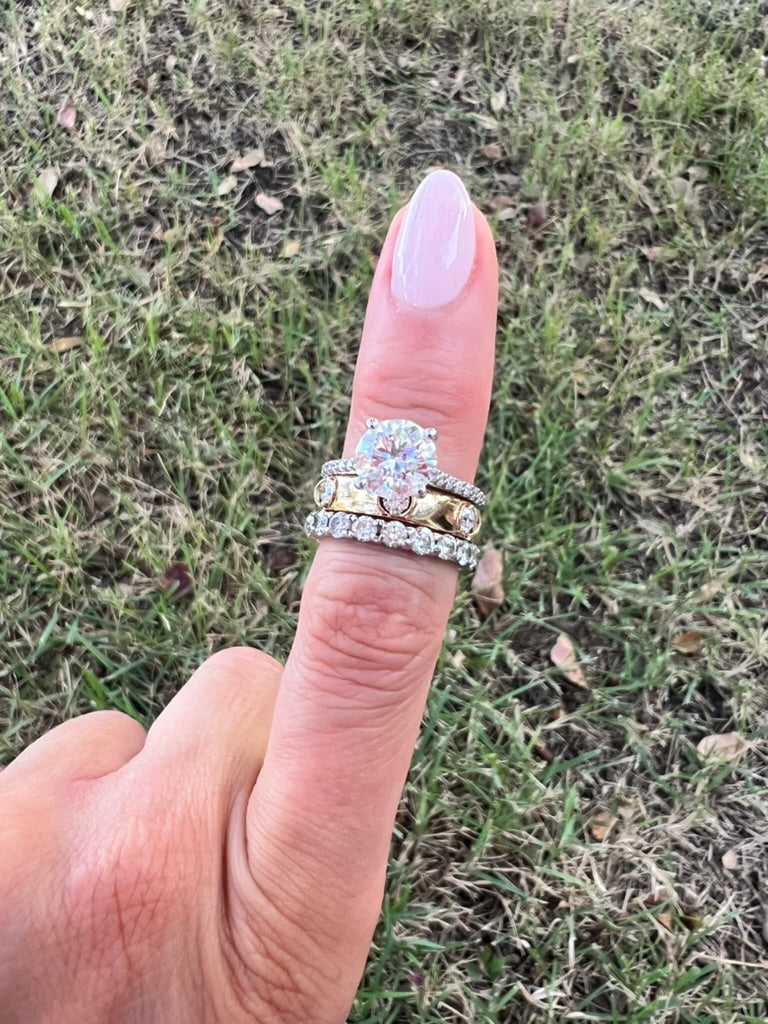 The Karat Concierge 3 stone floating diamond ring in 14K yellow gold worn on a finger against a grassy background.