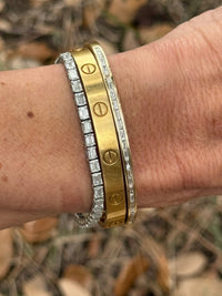 The Karat Concierge channel set baguette diamond bangle worn alongside a gold screw-motif bangle on a wrist.