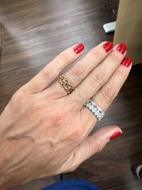 The Karat Concierge 18K gold bamboo ring featuring round sapphires, rubies, and emeralds stacked on a woman's finger.