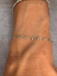 The Karat Concierge 14k yellow gold dangle bracelet with nine bezel-set diamonds worn on a wrist.