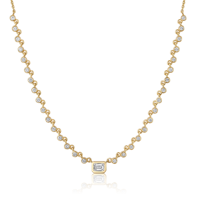 The Karat Concierge Peyton bezel set necklace in 14K yellow gold with emerald cut and round brilliant diamonds.