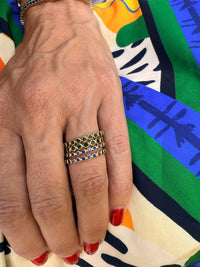 The Karat Concierge 14K yellow gold eternity bands featuring bezel-set emerald and sapphire gemstones on a hand.