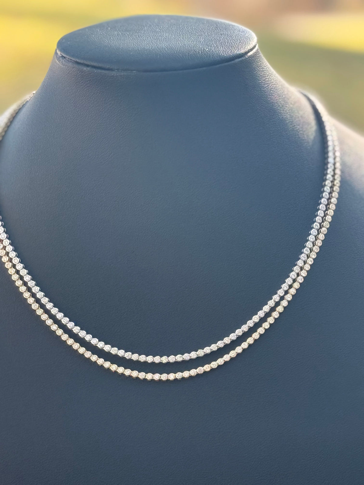 The Karat Concierge bezel set tennis necklace featuring 3.5 carats of sparkling stones on a black display bust.