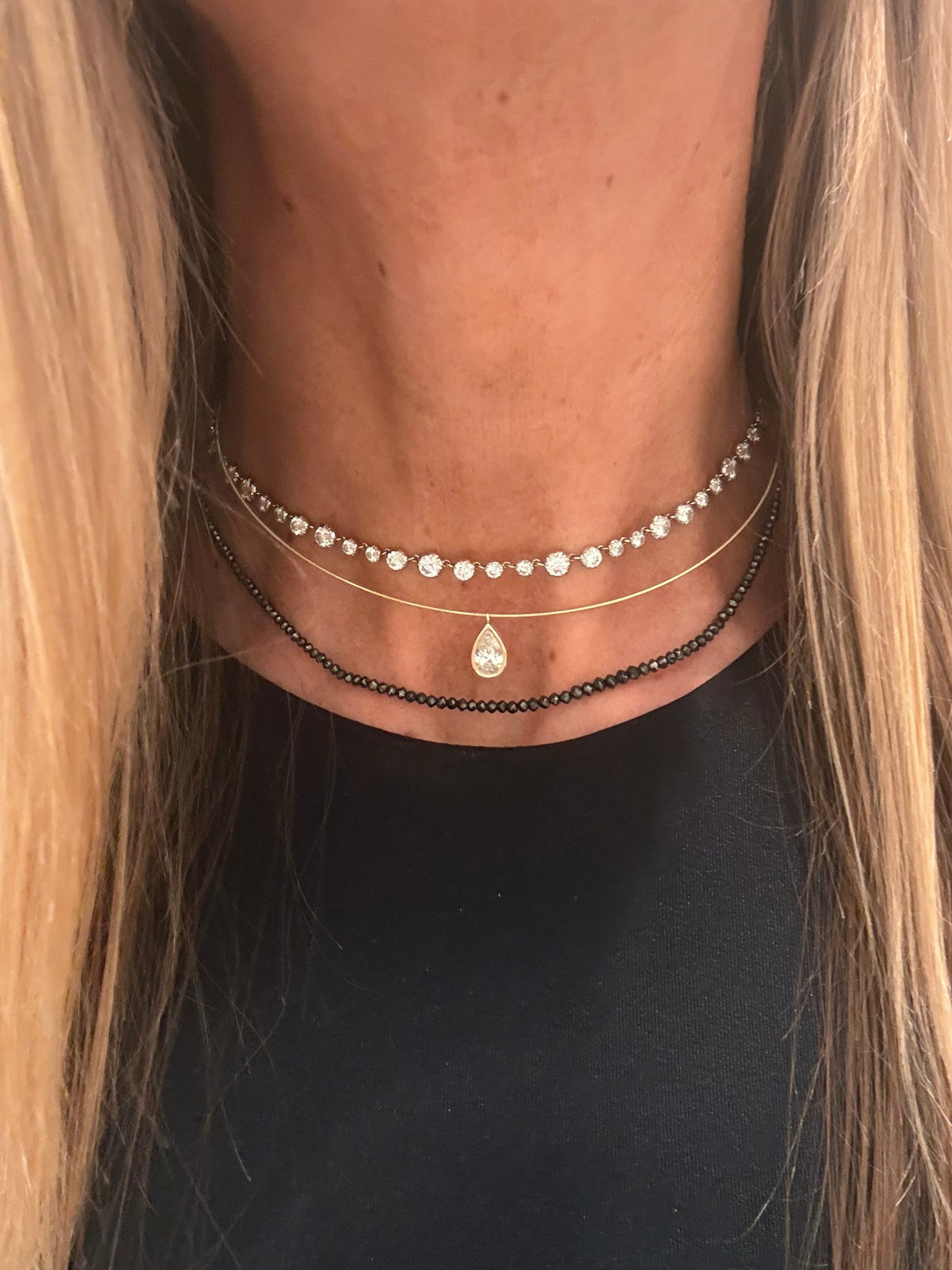The Karat Concierge black diamond beaded necklace layered with a diamond tennis choker and a pear-cut pendant.