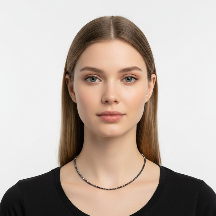 The Karat Concierge black diamond beaded necklace with 18K yellow gold extender worn by a model in a black top.