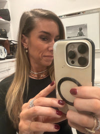 The Karat Concierge black diamond beaded necklace layered with gold chains on a woman taking a mirror selfie