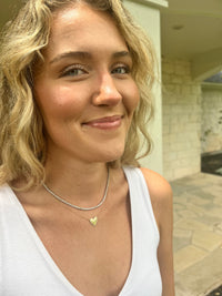 The Karat Concierge Amore Bubble Heart Necklace in 14K white gold with sparkling diamonds worn by a smiling woman.