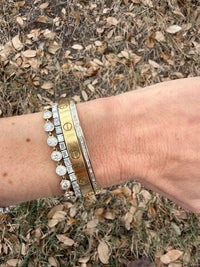 The Karat Concierge channel set baguette diamond bangle worn on a wrist with other gold and diamond bracelets.
