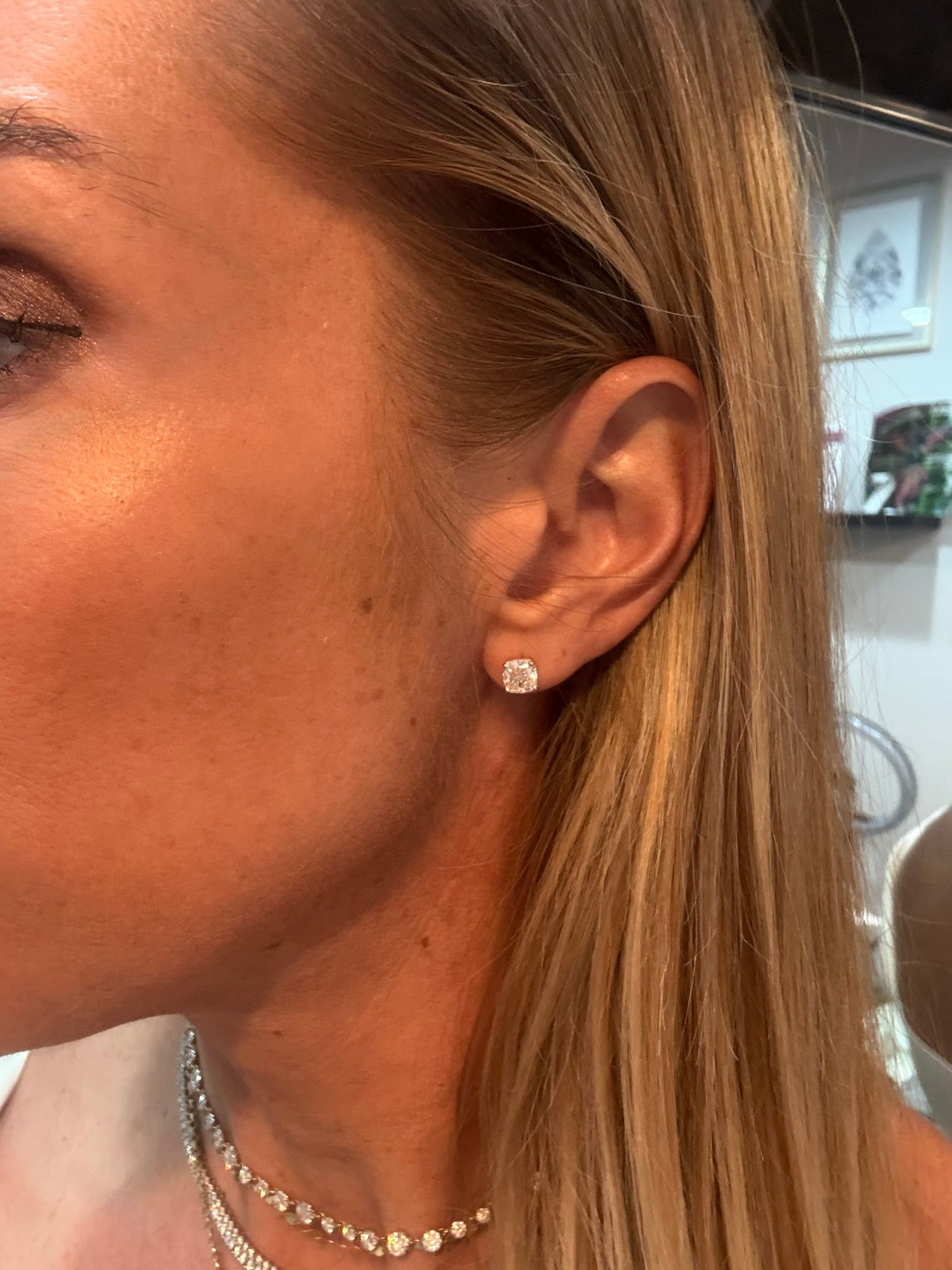 The Karat Concierge 2.08 CTW cushion cut diamond stud earrings in 18K yellow gold worn on a woman's ear.