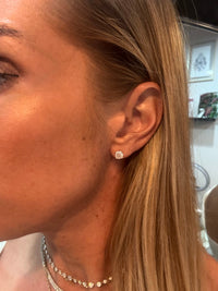The Karat Concierge 2.08 CTW cushion cut diamond stud earrings in 18K yellow gold worn on a woman's ear.