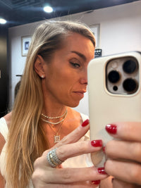The Karat Concierge cushion cut diamond stud earrings in 18K yellow gold worn by a woman taking a mirror selfie