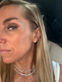 The Karat Concierge cushion cut diamond stud earrings in 18K yellow gold worn by a woman with blonde hair