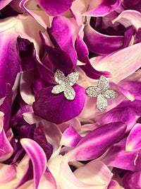 The Karat Concierge Lei Pave flower stud earrings in 14K white gold with sparkling diamonds on purple orchid petals.