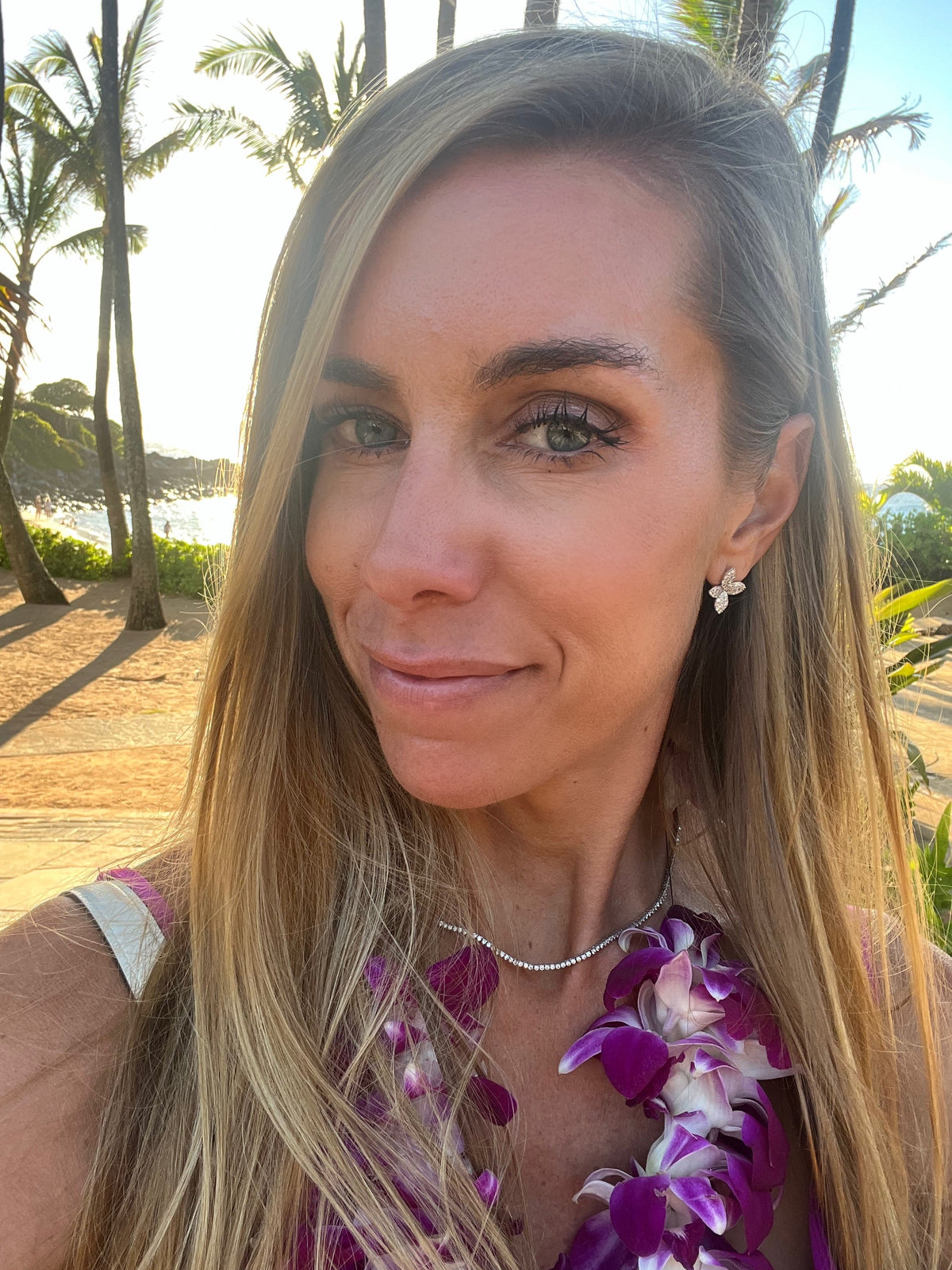 The Karat Concierge Lei Pave Flower Stud Earrings in 14K white gold with sparkling diamonds worn by a woman outdoors.