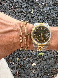 The Karat Concierge Charlotte diamond paperclip bracelet in 14K yellow gold worn on a wrist with a luxury watch.