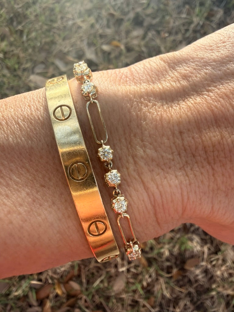 The Karat Concierge 14K yellow gold paperclip bracelet with natural diamonds worn on a wrist next to a gold bangle.