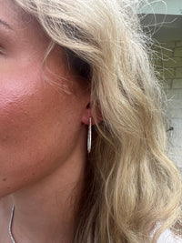 The Karat Concierge diamond tear shaped hoop earrings in 18K white gold worn by a woman with blonde hair.