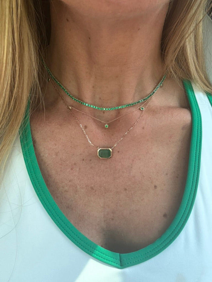 The Karat Concierge emerald bezel set necklace in 14K yellow gold layered with delicate green gemstone chains.
