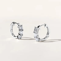 The Karat Concierge 14K white gold huggie earrings featuring three emerald cut diamonds on each hoop.